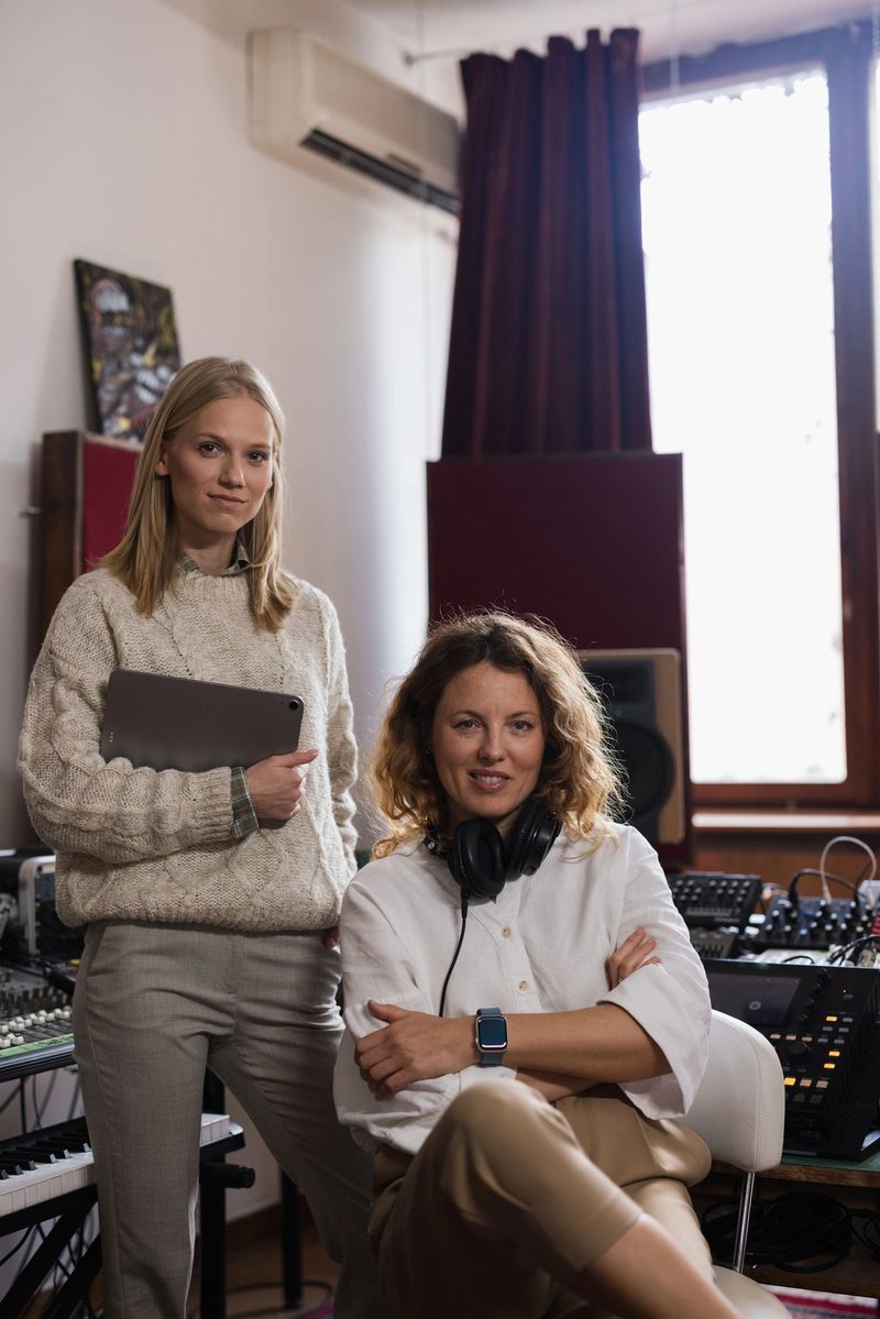 Two women, a sound engineer and a producer, collaborating in a music recording studio