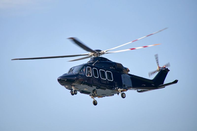 A black helicopter in the air, seen from the side and at a low angle