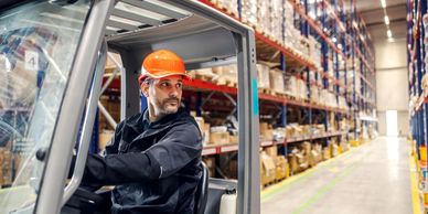 Worker operating forklift in warehouse.