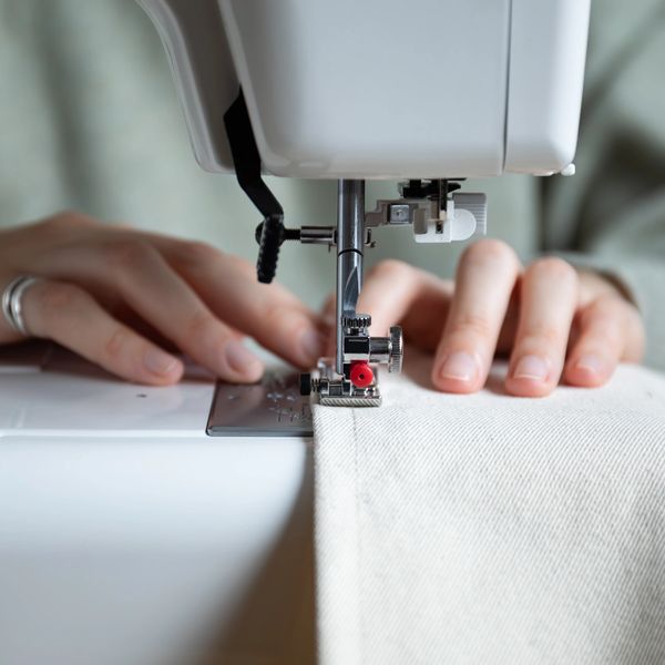Close-up of hands sewing fabric on a sewing machine.