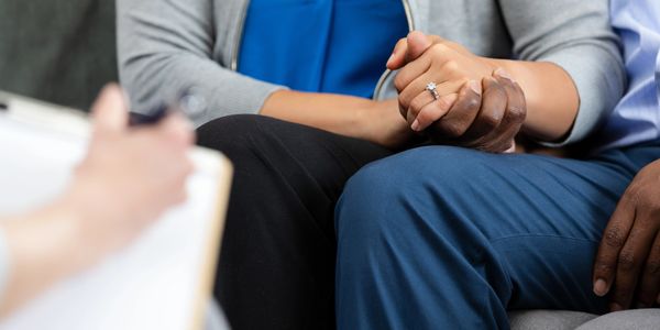 Couple holding hands during a counseling session, showing support and unity.
