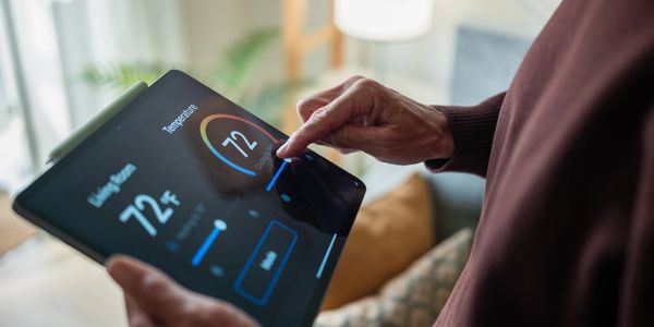 Person adjusting thermostat on tablet.