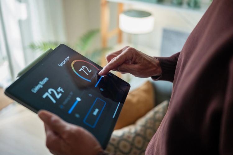 Person adjusting automation system setpoint on a tablet.