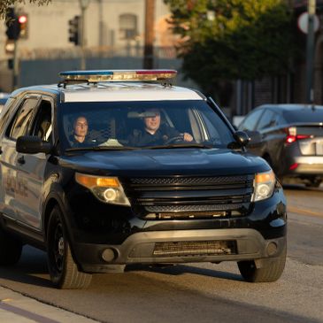 Police SUV driving on the street with two officers inside.