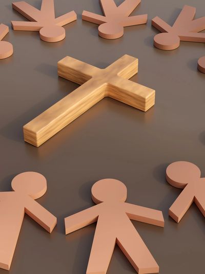 Wooden cross surrounded by human-shaped figures forming a circle.