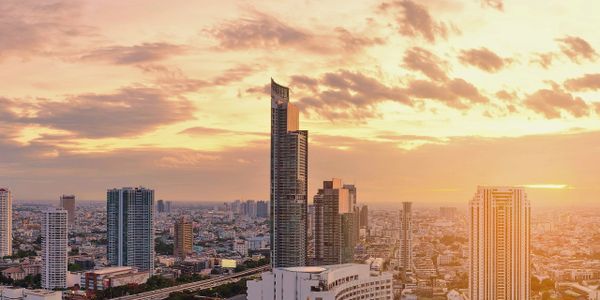 Sunset over a modern city skyline with a river and tall buildings.