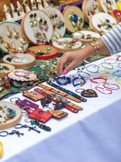 A person selecting jewelry from a colorful market stall.