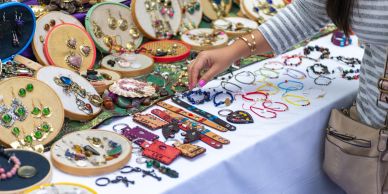 Hand browsing colorful jewelry on display.