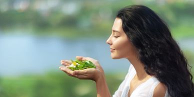 Woman enjoying the scent of fresh herbs outdoors.