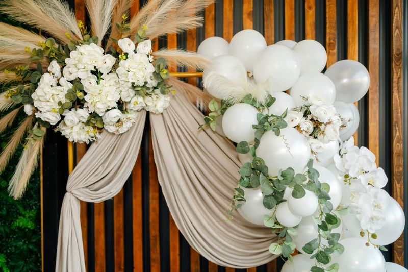 Elegant decoration features white balloons and flowers arranged thoughtfully on a backdrop for a wedding event.