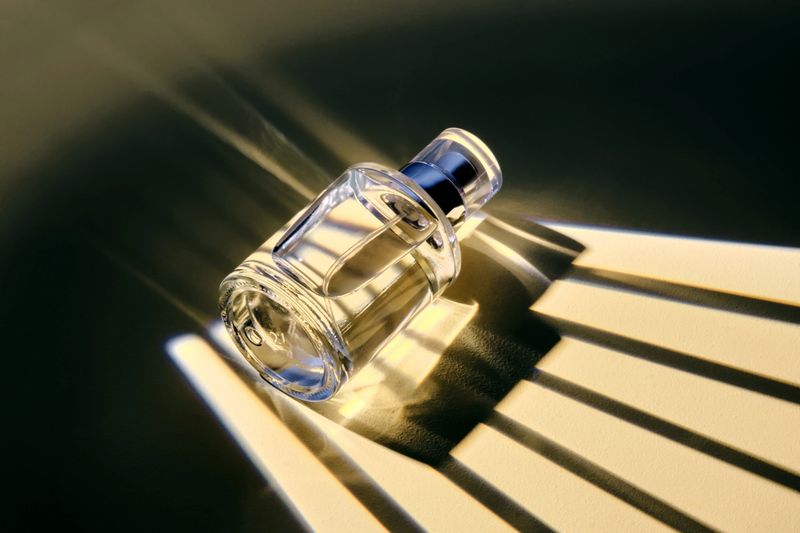 A bottle of perfume spray in an interesting light with stripes of shadows. High quality photo.
