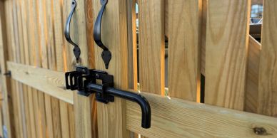 Close-up of black metal latch and handles on a wooden gate.