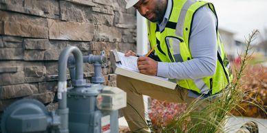 Worker inspecting a gas meter outdoors.