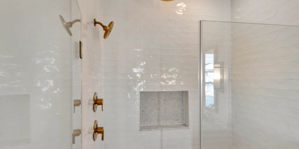 Modern shower with gold fixtures and glass enclosure.