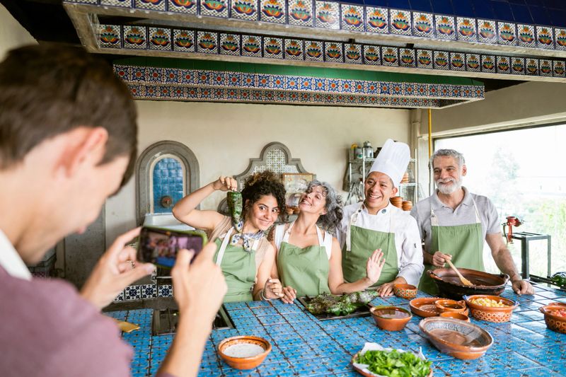 Tourists taking a group photo with a chef during a Mexican Cooking Class in a commercial kitchen