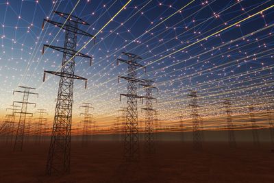 Power lines at sunset with a network of glowing connections above.