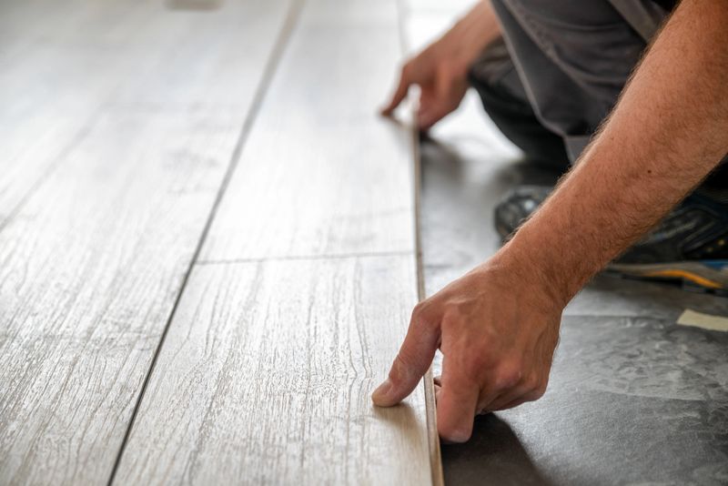 Installation of a new laminate floating floor in the house. Hands of the worker.Installation of a new laminate floating floor in the house