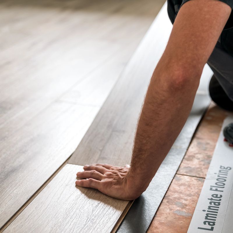 Installation of a new laminate floating floor in the house by worker