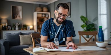 Smiling male doctor reviewing documents at home.