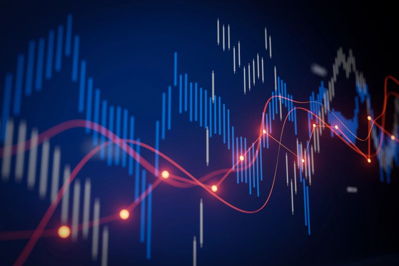 Colorful candlestick and line graphs show financial market trends on a dark background. The data visualization highlights price fluctuations and market patterns.