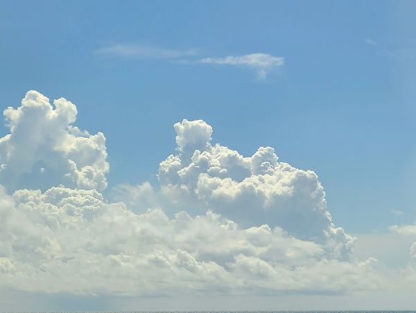 Fluffy white clouds under a clear blue sky.