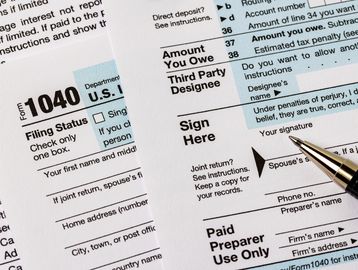 Form 1040 tax document with pen, representing individual and business tax preparation services