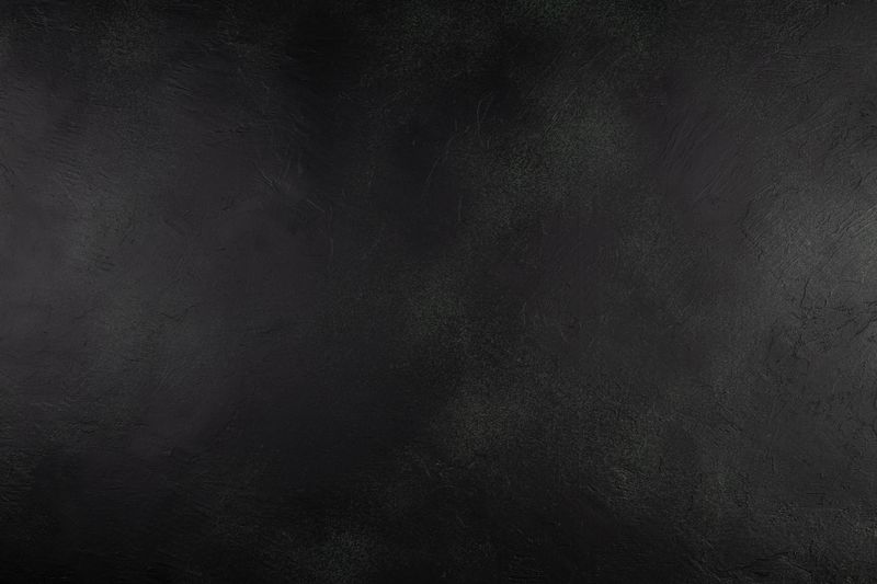 Dark black textured background with subtle rough patterns and empty copy space, ideal for product presentation, food styling, advertising designs, banners, or graphic templates. Suitable for commercial use as a clean and modern backdrop