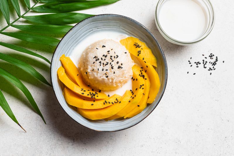Mango Sticky Rice with coconut milk and black sesame seeds, top view, close up. Traditional thai food. Khao niao mamuang.