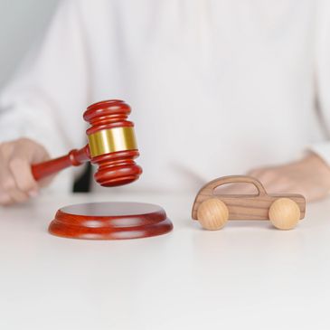 A gavel striking near a wooden toy car, symbolizing legal decisions in automotive matters.