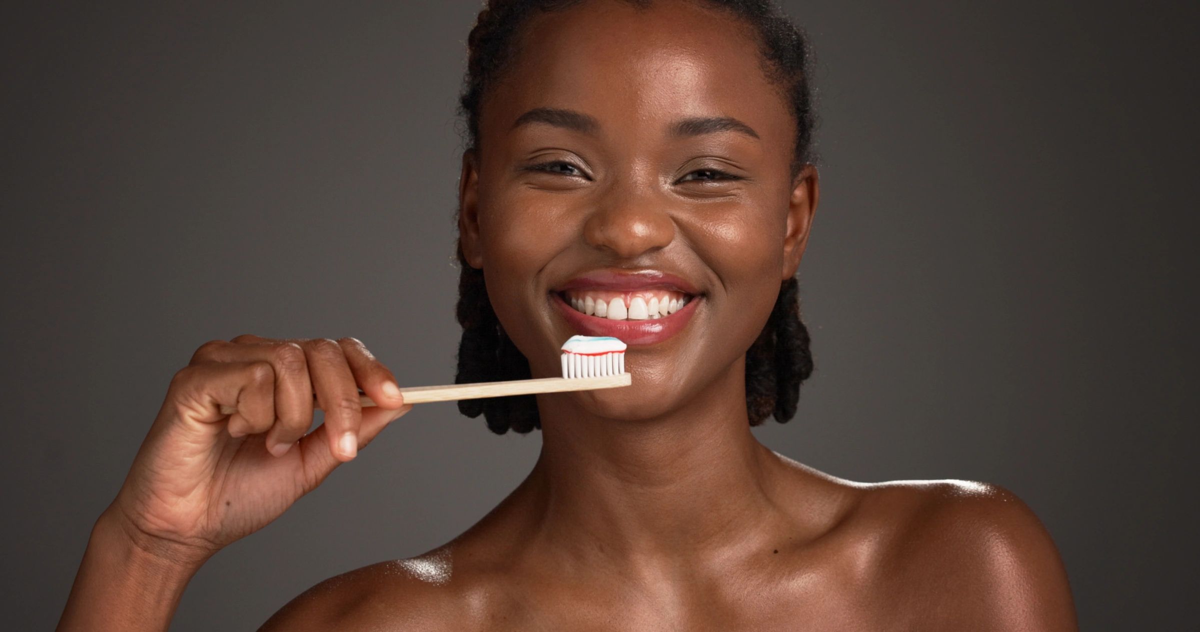 Smiling woman holding toothbrush with toothpaste.