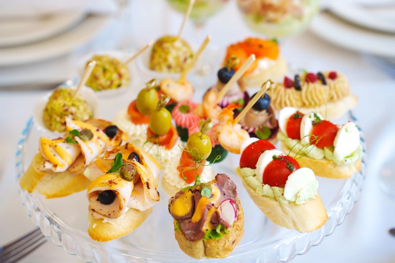 A beautiful display of canapes is arranged on a glass stand. Different flavors and colors create an inviting atmosphere for any event or celebration.