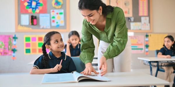 Teacher helping young student in classroom.