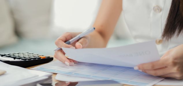 Person reviewing documents with a calculator nearby.