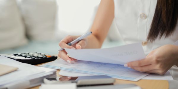 Person reviewing financial documents with a pen.