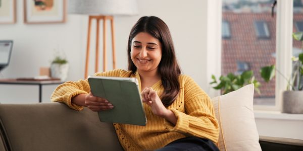 Woman sitting on sofa with a tablet 