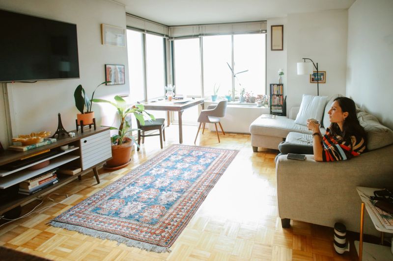 Woman enjoying her TV program from a cozy sofa in a tidy, stylish living room. Perfect for concepts of streaming, comfort, leisure, and modern daily life.