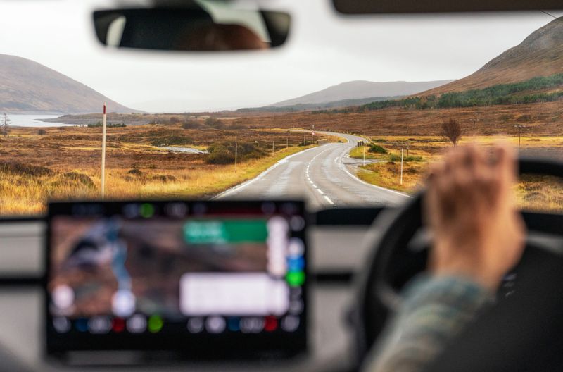 An interior car view as the driver steers during a journey along a country road in Wester Ross, in the north west of Scotland.
