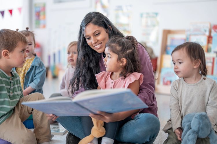Teacher reading a book to young children in a classroom.