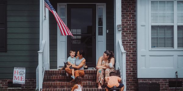 Family enjoying time together on their front porch with an American flag.