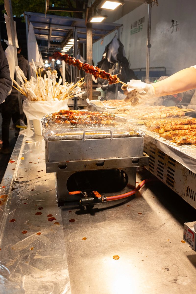 Street food vendor in a Korean night market grilling various skewers, showcasing traditional cuisine and the lively atmosphere