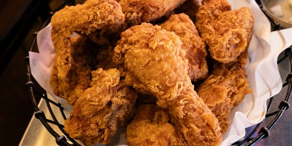 Basket of crispy, golden fried chicken drumsticks.
