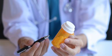 A doctor holding a prescription pill bottle and pen.