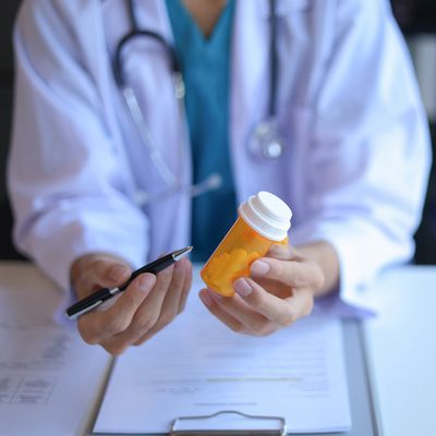 Doctor explaining medication with a pill bottle and pen.