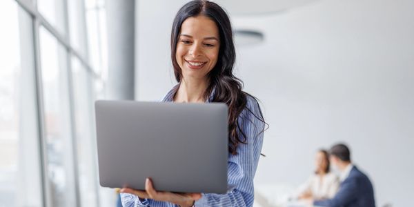 Smiling woman using a laptop in a bright office.