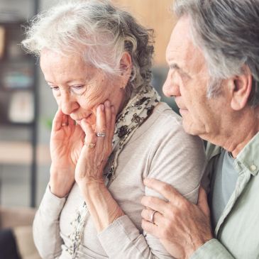 Elderly man comforting a distressed elderly woman.