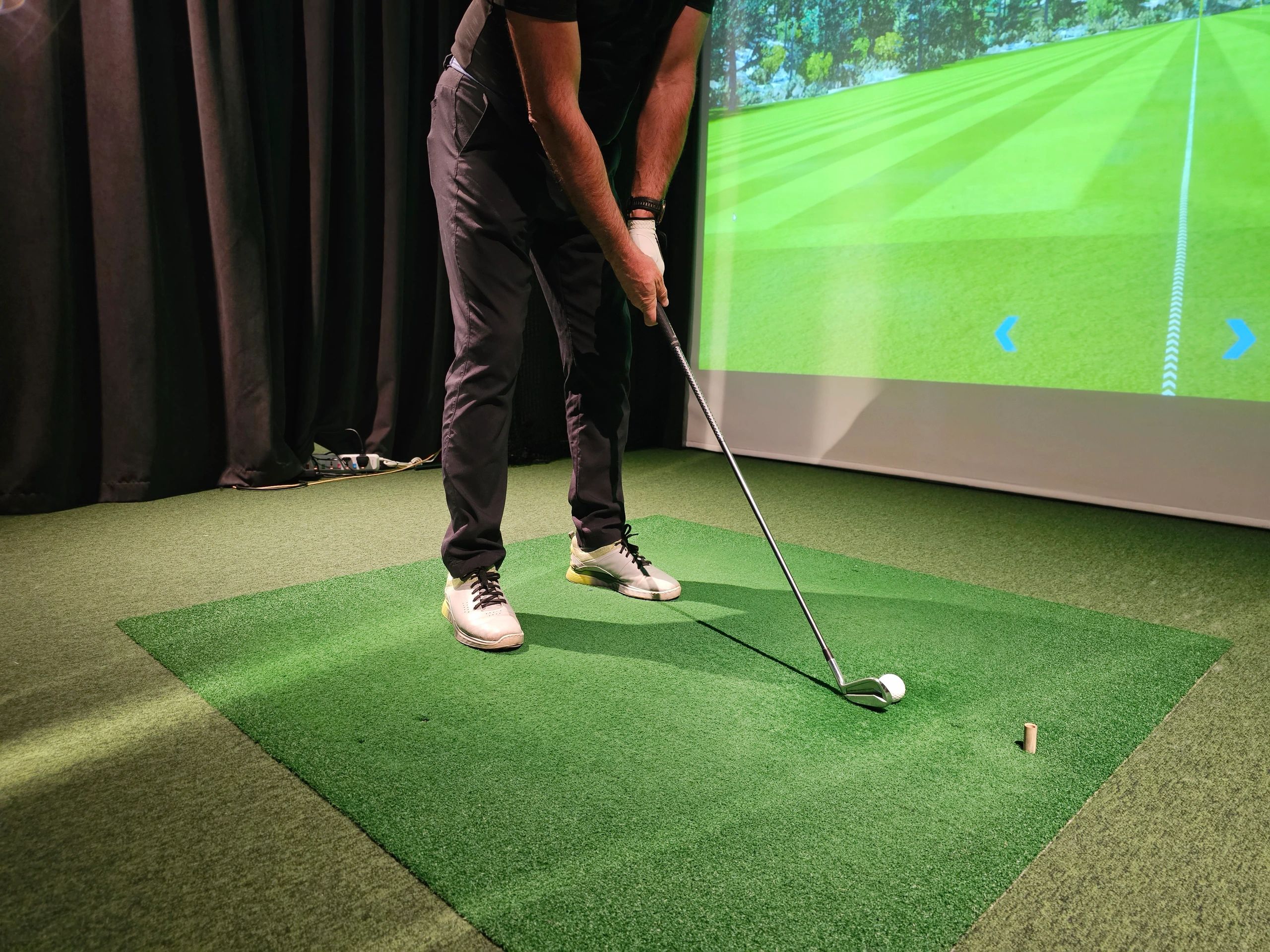 Man preparing to play golf using a golf simulator indoors.