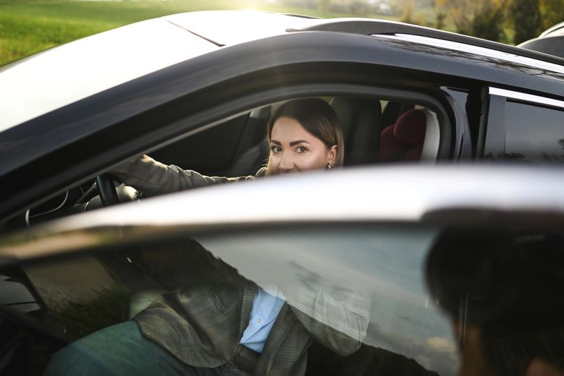Young adult woman looking back, enjoying a countryside road trip