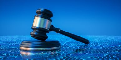 A judge's gavel resting on a sound block with a blue digital circuit background.