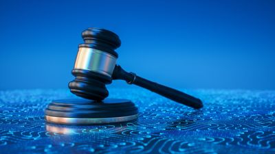 A wooden judge's gavel on a sound block with a blue background.