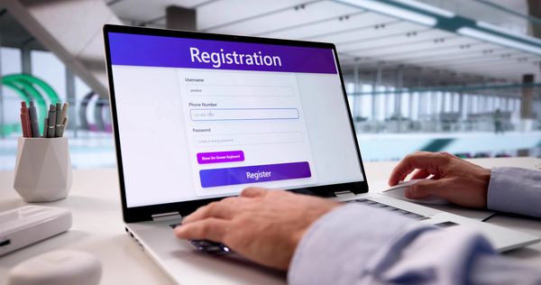 Person registering on a laptop with a registration form on the screen.